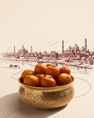 Gulab jamun in a brass bowl on an engraved Mughal city skyline
